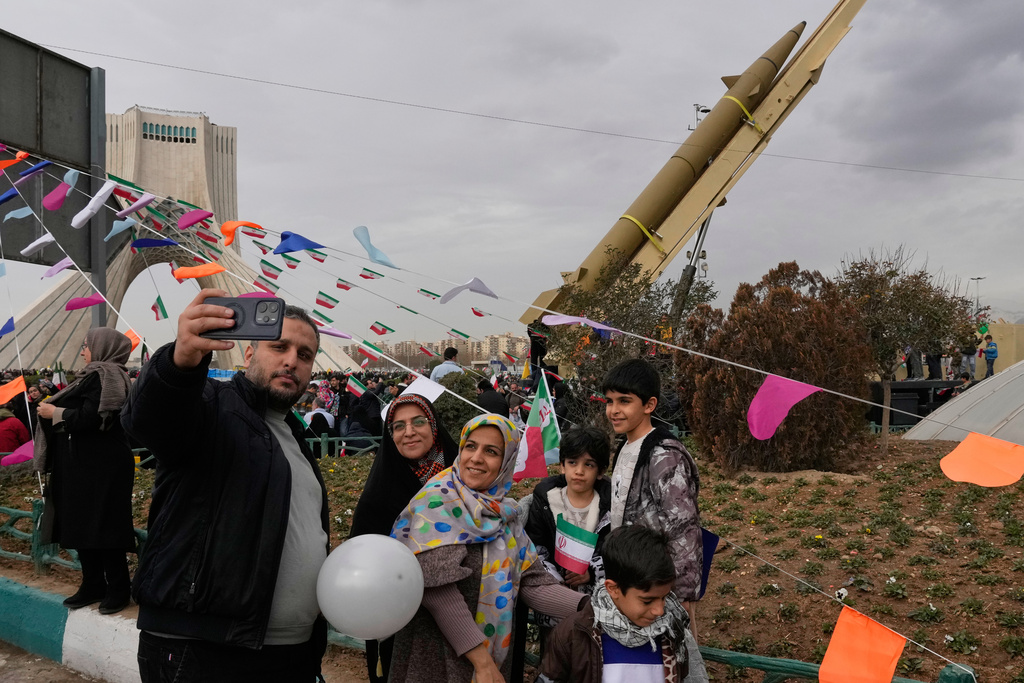 People take a selfie in front of an Iranian-built missile during an annual rally marking 1979 Islamic Revolution at the Azadi (Freedom) sq. in Tehran, Iran, Wednesday, Feb. 11, 2026. (AP Photo/Vahid Salemi)