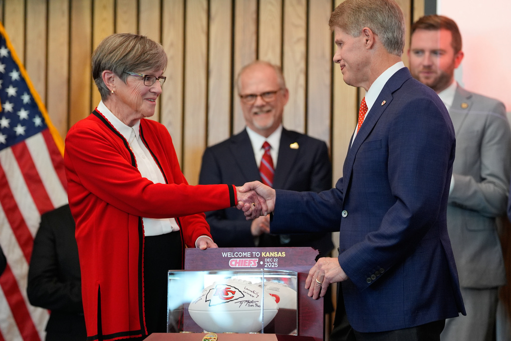 Kansas City Chiefs owner Clark Hunt, right, and Kansas Gov. Laura Kelly, shake hands during an event announcing the team will leave Arrowhead Stadium in Kansas City, Mo. for a new stadium that will be built across the Kansas-Missouri state line and be ready for the start of the 2031 season, during an event Monday, Dec. 22, 2025 in Topeka, Kan. (AP Photo/Charlie Riedel)
