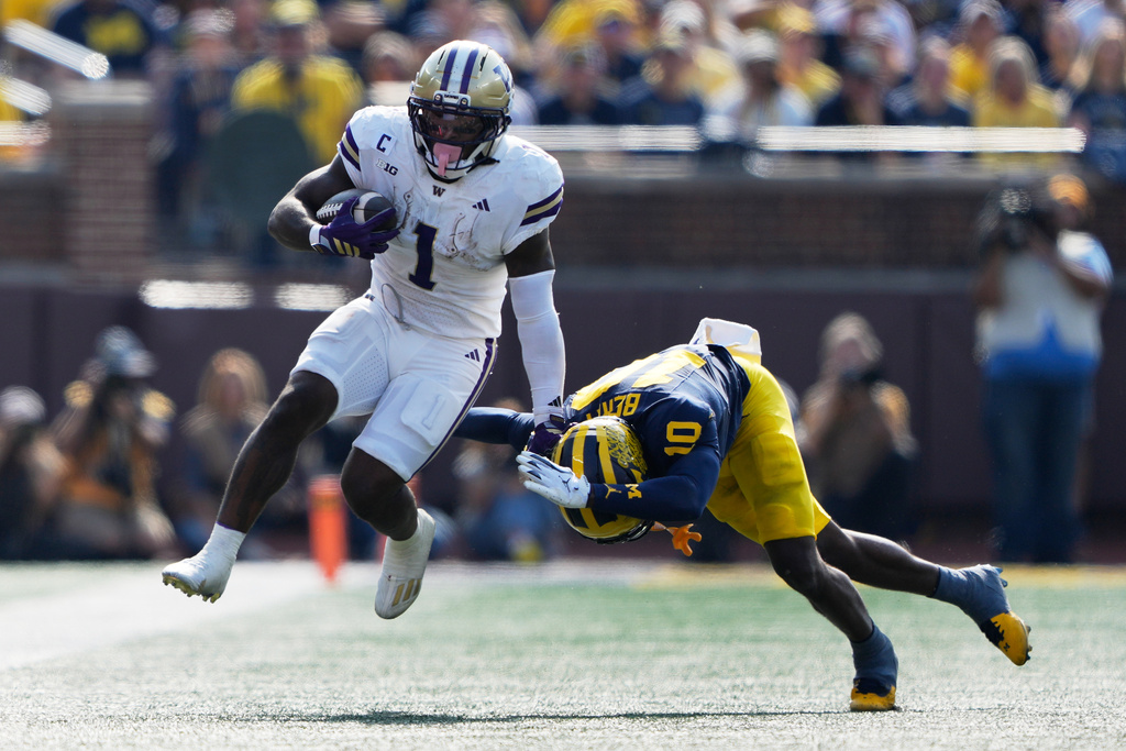 Washington running back Jonah Coleman, left, runs against Michigan defensive back Zeke Berry during the first half of an NCAA college football game, Saturday, Oct. 18, 2025, in Ann Arbor, Mich. (AP Photo/Ryan Sun)