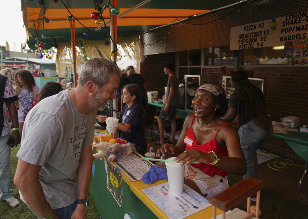 Chloe Mutombo, right, daughter of immigrant parents from Congo, volunteers at the St. Jude Catholic Church's Sweet Corn Festival, on Saturday, Aug. 9, 2025, in Cedar Rapids, Iowa. (AP Photo/Jessie Wardarski)