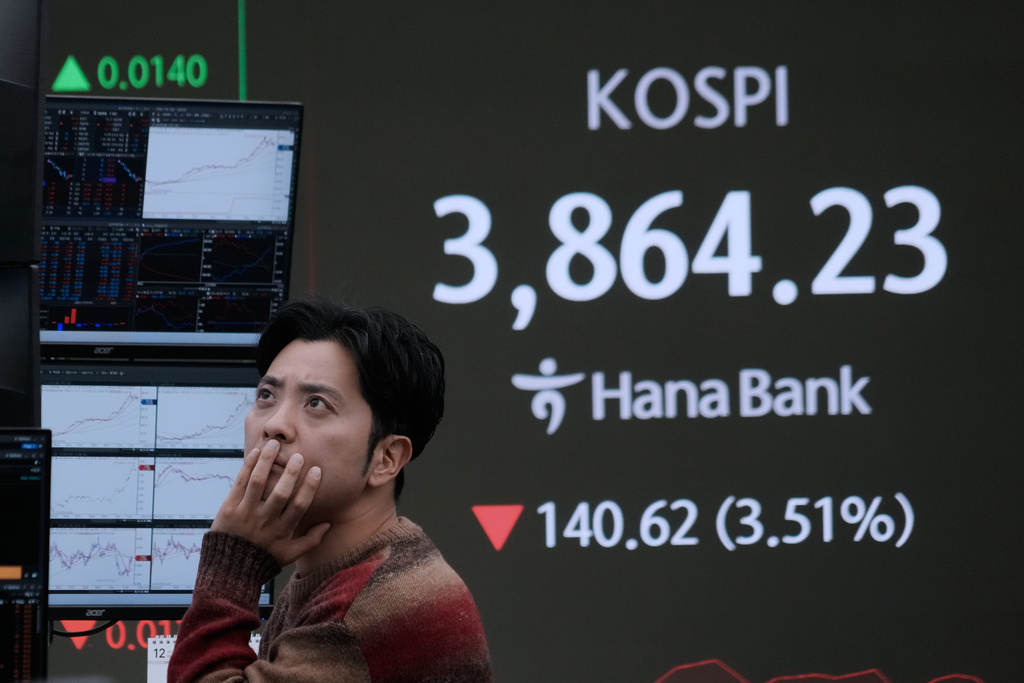 A currency trader watches monitors near a screen showing the Korea Composite Stock Price Index (KOSPI) at the foreign exchange dealing room of the Hana Bank headquarters in Seoul, South Korea, Friday, Nov. 21, 2025. (AP Photo/Ahn Young-joon)