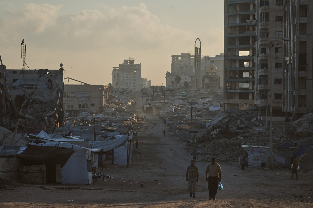 Palestinians walk along a street surrounded by buildings destroyed in Israeli military strikes during the Israel-Hamas war, in Gaza City, Thursday, July 2, 2026. (AP Photo/Jehad Alshrafi)