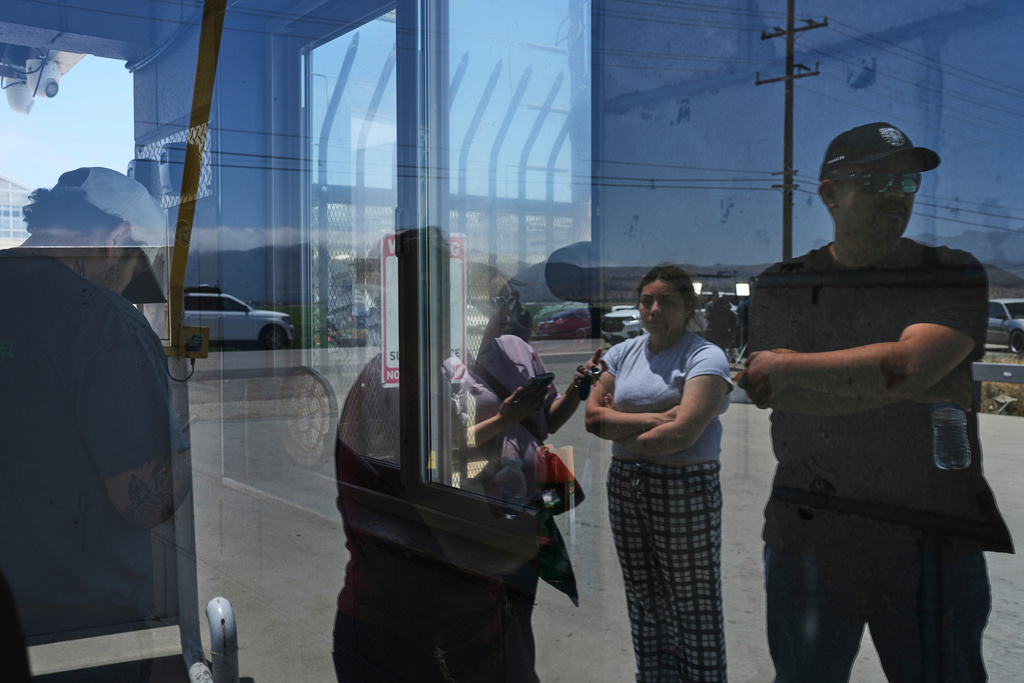 FILE - People wait outside of Glass House Farms, a day after an immigration raid on the facility, July 11, 2025, in Camarillo, Calif. (AP Photo/Jae C. Hong, File)