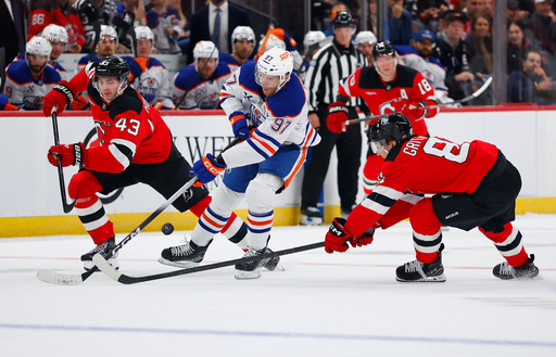 CORRECTS YEAR TO 2025, NOT 2024 - Edmonton Oilers center Connor McDavid (97) plays the puck ahead of New Jersey Devils' Luke Hughes (43) and Arseny Gritsyuk (81) during the first period of an NHL hockey game, Saturday, Oct. 18, 2025, in Newark, N.J. (AP Photo/Noah K. Murray) CORRECTS YEAR TO 2025, NOT 2024 - Edmonton Oilers center Connor McDavid (97) plays the puck ahead of New Jersey Devils' Luke Hughes (43) and Arseny Gritsyuk (81) during the first period of an NHL hockey game, Saturday, Oct. 18, 2025, in Newark, N.J. (AP Photo/Noah K. Murray)