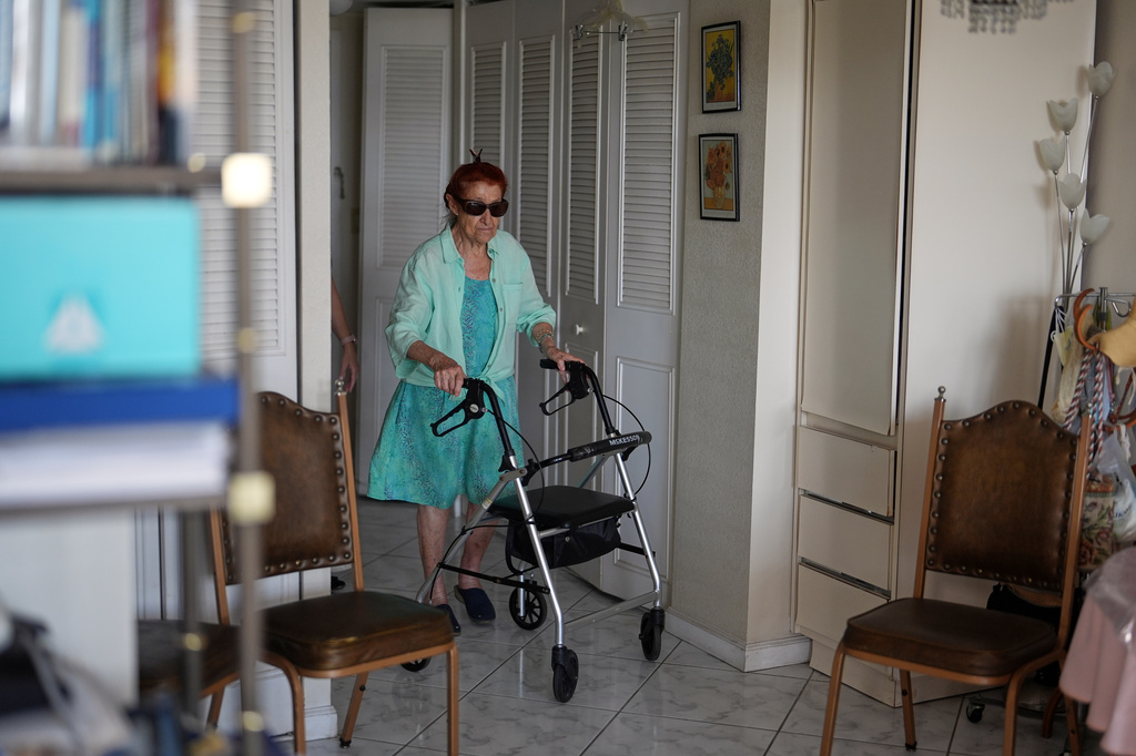 Anna Fischbein, 86, walks inside her apartment during an interview about the loss of a beloved Haitian home health care worker whose Temporary Protected Status expired this week, Thursday, July 30, 2026, in Sunny Isles Beach. (AP Photo/Rebecca Blackwell).