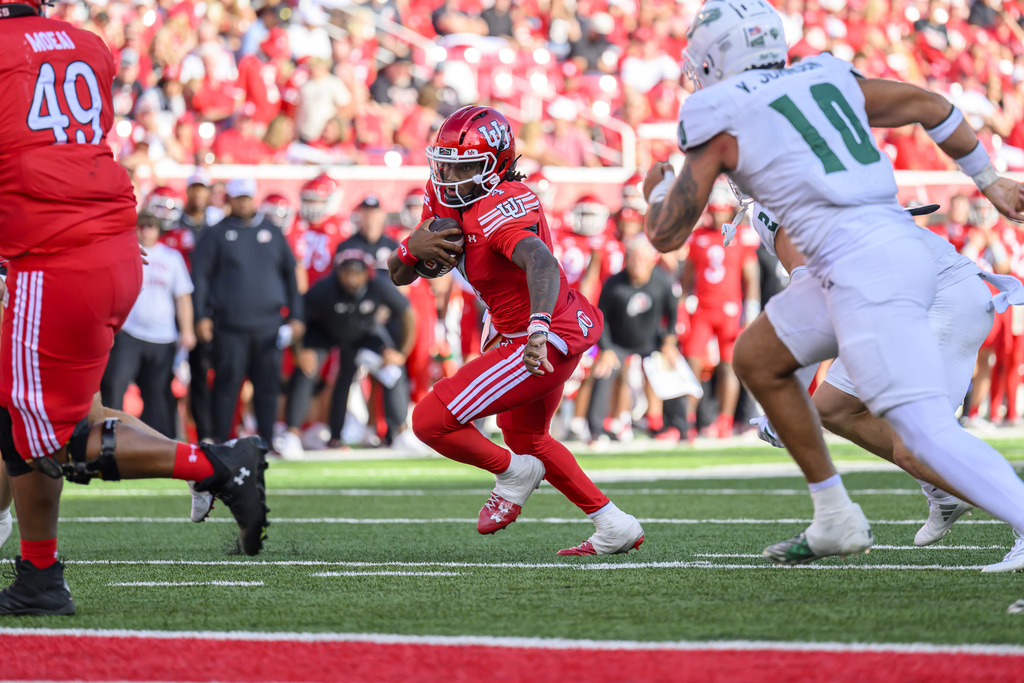 Utah quarterback Devon Dampier, center, runs the ball during an NCAA college football game against Cal Poly, Saturday, Sept. 6, 2025, in Salt Lake City, Utah. (AP Photo/Tyler Tate)