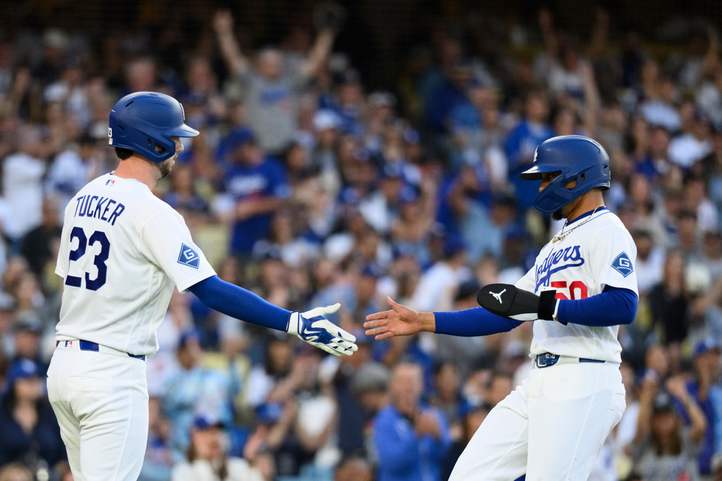 Los Angeles Dodgers' Mookie Betts, right, celebrates with Kyle Tucker, left, after scoring on a two-run single hit by Max Muncy during the first inning of a baseball game against the Baltimore Orioles in Los Angeles, Friday, June 19, 2026. (AP Photo/Kyusung Gong)
