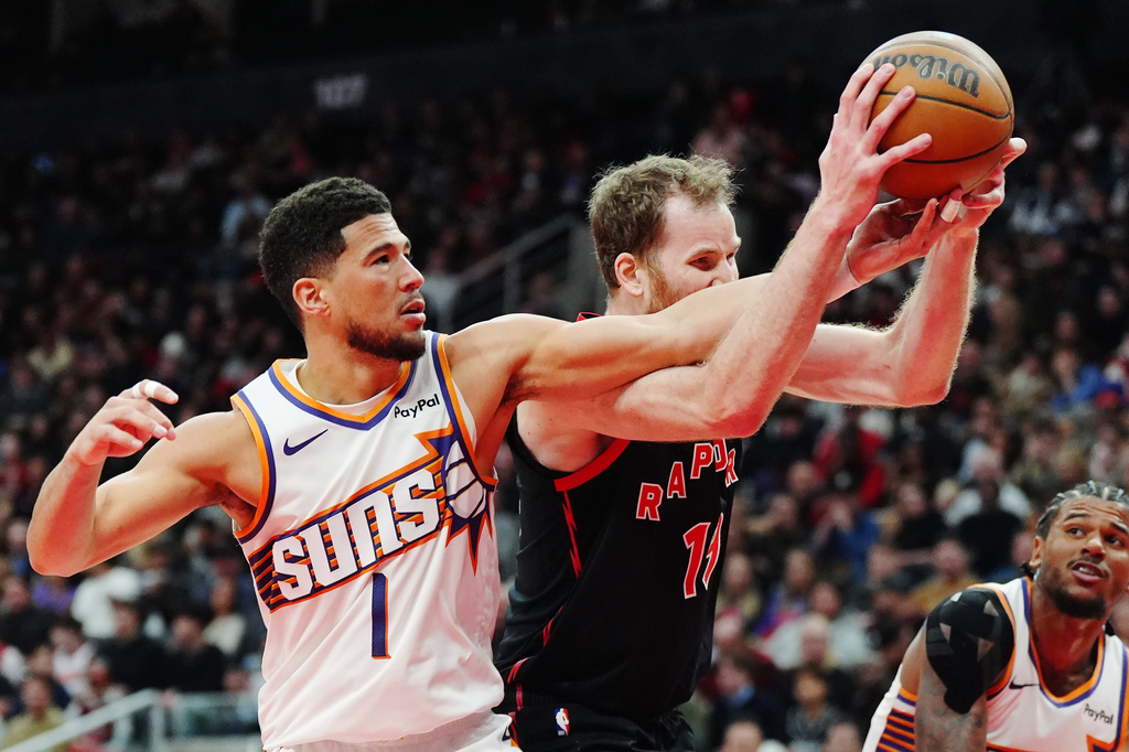 Phoenix Suns' Devin Booker (1) and Toronto Raptors' Jakob Poeltl (19) battle for the ball during the first half of an NBA basketball game in Toronto, Friday, March 13, 2026. (Frank Gunn/The Canadian Press via AP)