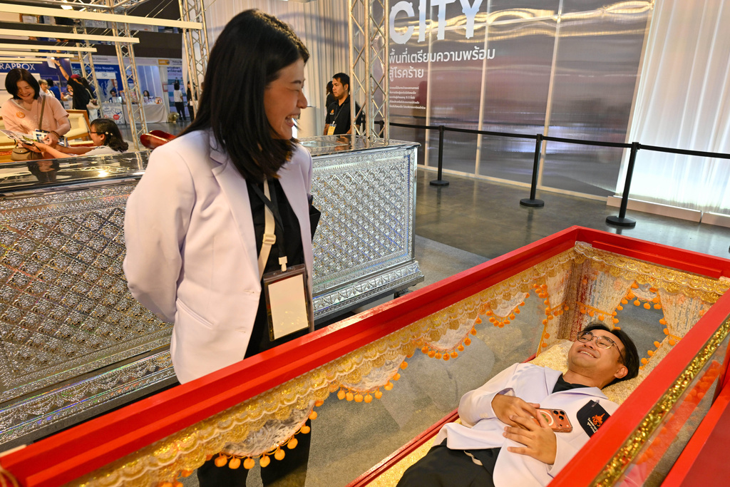A visitor tries out a coffin at Death Fest in Nonthaburi, Thailand, Friday, March 13, 2026. (AP Photo/Kittinun Rodsupan)