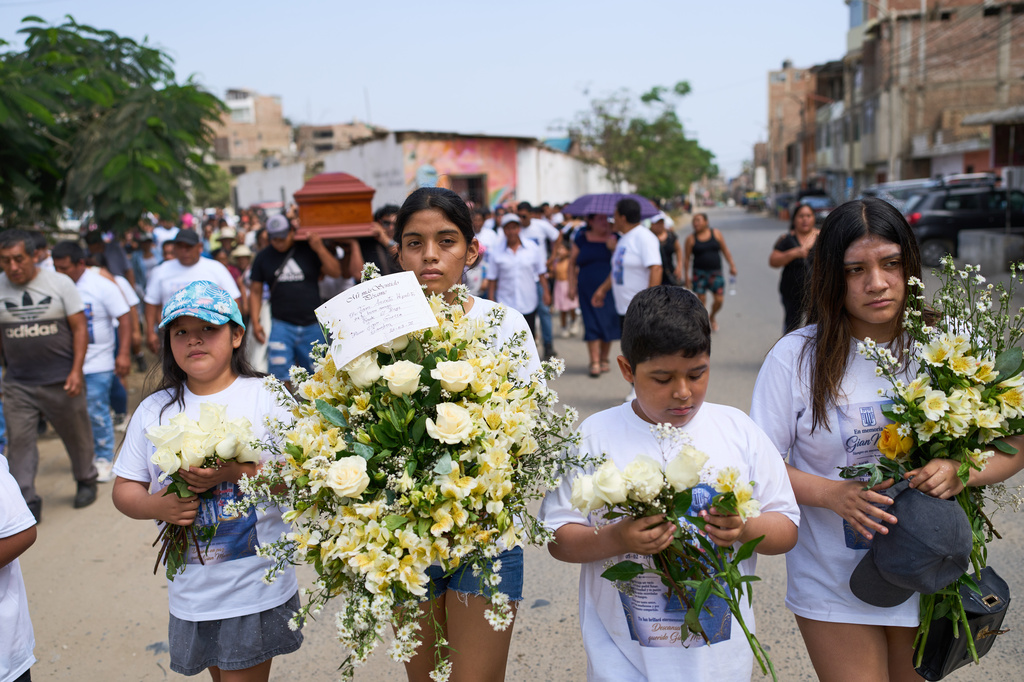 Children carry flowers during the funeral of Gian Marco Garcia, who was killed by a hitman in El Porvenir, a district of Trujillo, Peru, Monday, May 25, 2026. (AP Photo/Rodrigo Abd)