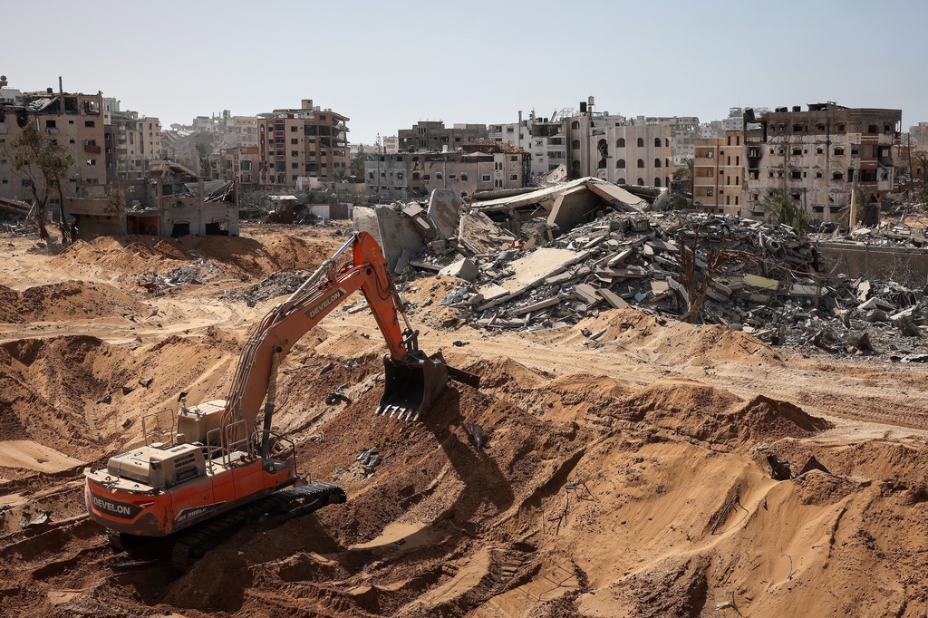 This picture taken during a media tour organised by the Israeli army, shows a bulldozer digging amid war-damaged buildings in the vicinity of the Jordanian Field Hospital in Gaza City, Friday, Oct. 3, 2025. (Jack Guez/Pool Photo via AP)