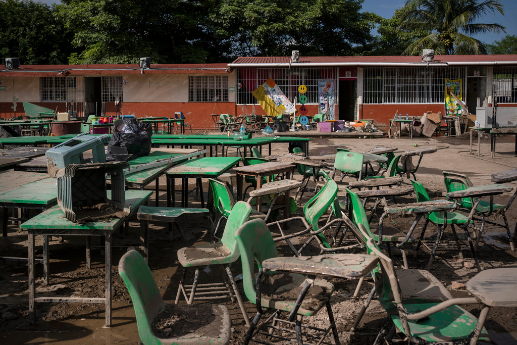 Desks removed from a flooded school sit under the sun in Poza Rica, Veracruz state, Mexico, Wednesday, Oct. 15, 2025, after torrential rain. (AP Photo/Felix Marquez)