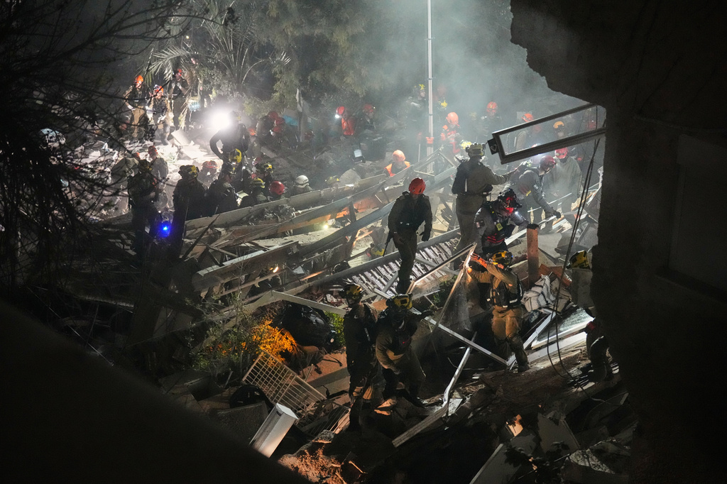 Israeli security forces and rescue teams work amid the rubble of a residential building struck by an Iranian missile in Haifa, Israel, Sunday, April 5, 2026. (AP Photo/Ariel Schalit)