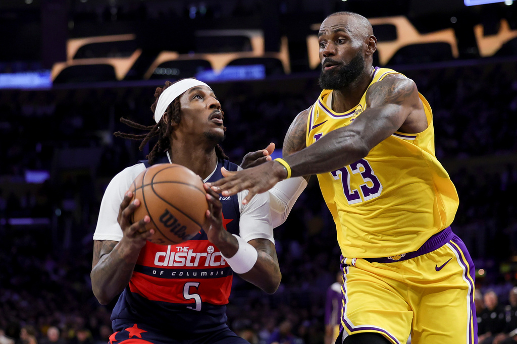 Washington Wizards guard Jamir Watkins, left, drives against Los Angeles Lakers forward LeBron James during the first half of an NBA basketball game Monday, March 30, 2026, in Los Angeles. (AP Photo/Ryan Sun)