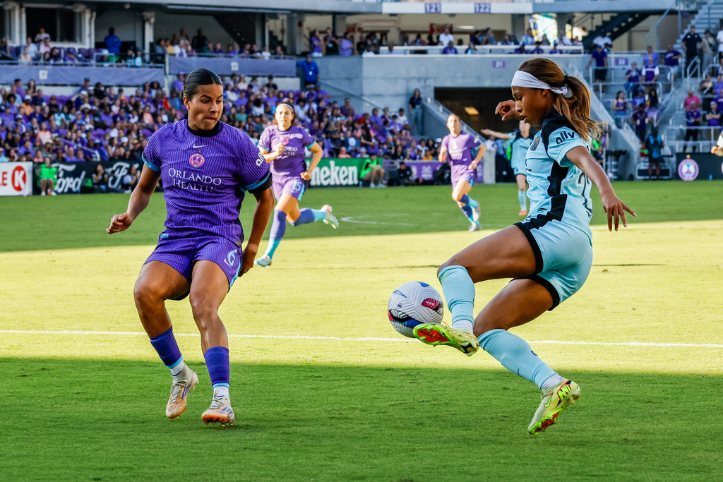 NJ/NY Gotham FC forward Midge Purce, right, controls the ball as she is defended by Orlando Pride defender Emily Sams, left, during the first half of an NWSL women's semifinal soccer match, Sunday, Nov. 16, 2025, in Orlando, Fla. (AP Photo/Kevin Kolczynski)