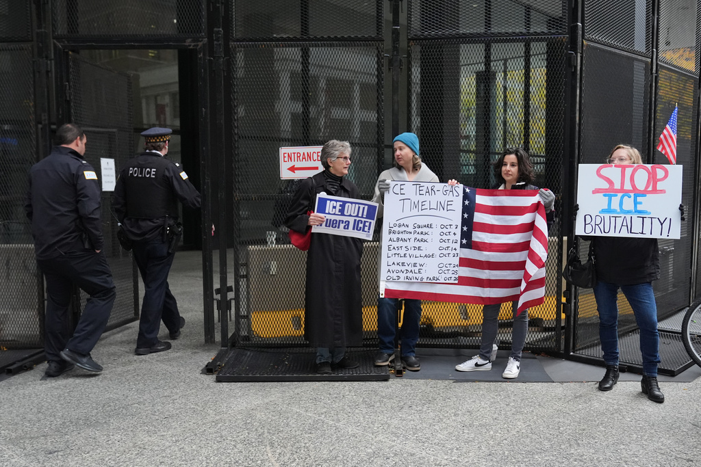 People hold signs as they wait for U.S. Customs and Border Patrol Gregory Bovino outside federal court in Chicago, Tuesday, Oct. 28, 2025. (AP Photo/Nam Y. Huh)
