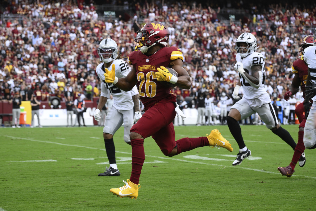 Washington Commanders running back Jeremy McNichols (26) breaks free from Las Vegas Raiders defense and runs in a touchdown during the first half of NFL football game Sunday, Sept. 21, 2025, in Landover, Md. (AP Photo/Nick Wass)