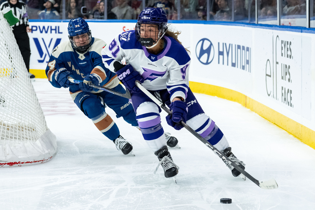 Minnesota Frost's Peyton Anderson (91) skates with the puck as Vancouver Goldeneyes' Anna Meixner (94) defends during the third period of a PWHL hockey game in Vancouver, British Columbia, Saturday, March 21, 2026. (Ethan Cairns/The Canadian Press via AP)