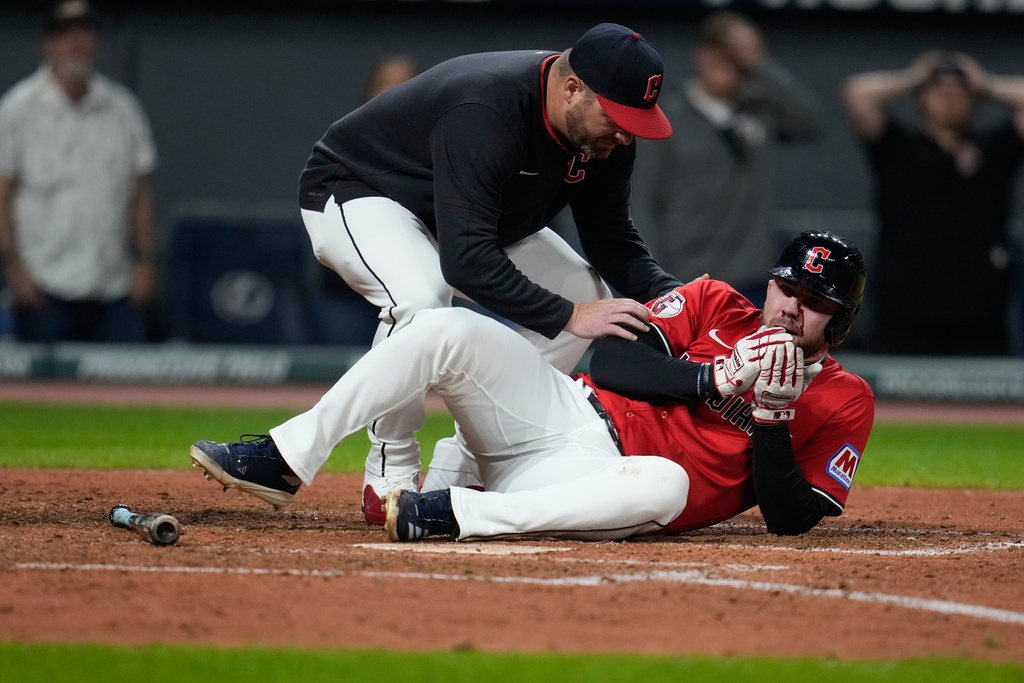 Cleveland Guardians manager Stephen Vogt, left, attends to David Fry after Fry was hit in the face with his own bunt in the sixth inning of a baseball game against the Detroit Tigers in Cleveland, Tuesday, Sept. 23, 2025. (AP Photo/Sue Ogrocki)