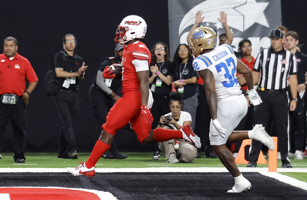 UNLV running back Keyvone Lee, left, scores a touchdown past UCLA linebacker Isaiah Chisom (32) during the first half of an NCAA college football game Saturday, Sept. 6, 2025, in Las Vegas. (Steve Marcus/Las Vegas Sun via AP)
