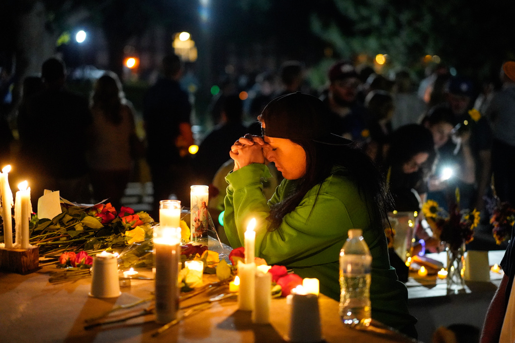 A woman prays during a candlelight vigil Tuesday, Aug. 4, 2026, in Twin Falls, Idaho, to honor the victims of a recent shooting at a local In-N-Out Burger. (AP Photo/Andrew Eakin)
