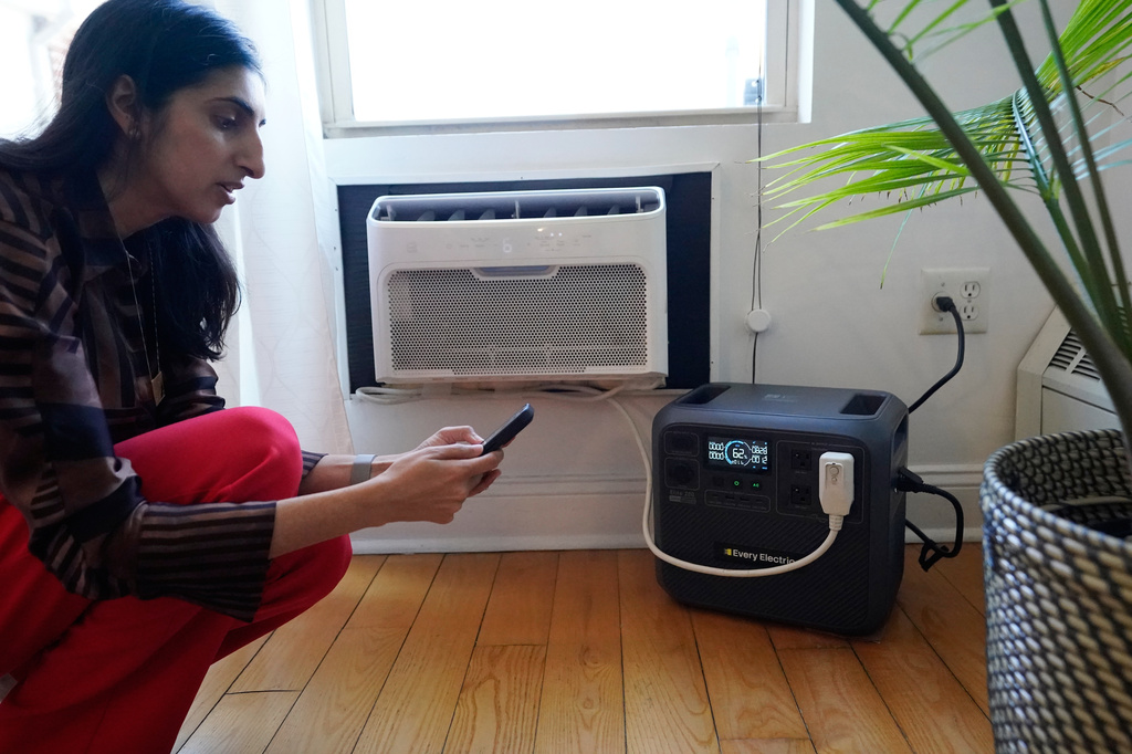 Sonam Velani hooks up a battery from Every Electric to power an air conditioner as part of a pilot program with the city's energy company Con Edison to reduce pressure on the electrical grid Monday, April 27, 2026, in the Brooklyn borough of New York. (AP Photo/Alyssa Goodman)