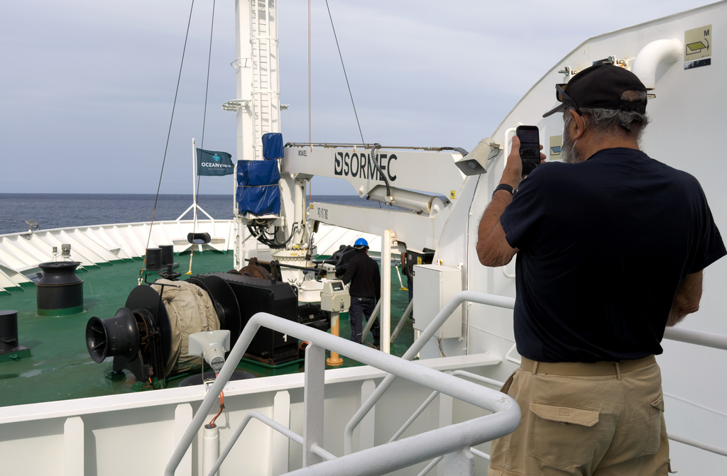 A passenger on the the hantavirus-stricken cruise ship, MV Hondius, takes a photo of the ship's weighing anchor in Praia, during the voyage to Spain's port of Tenerife, May 6, 2026. (AP Photo)
