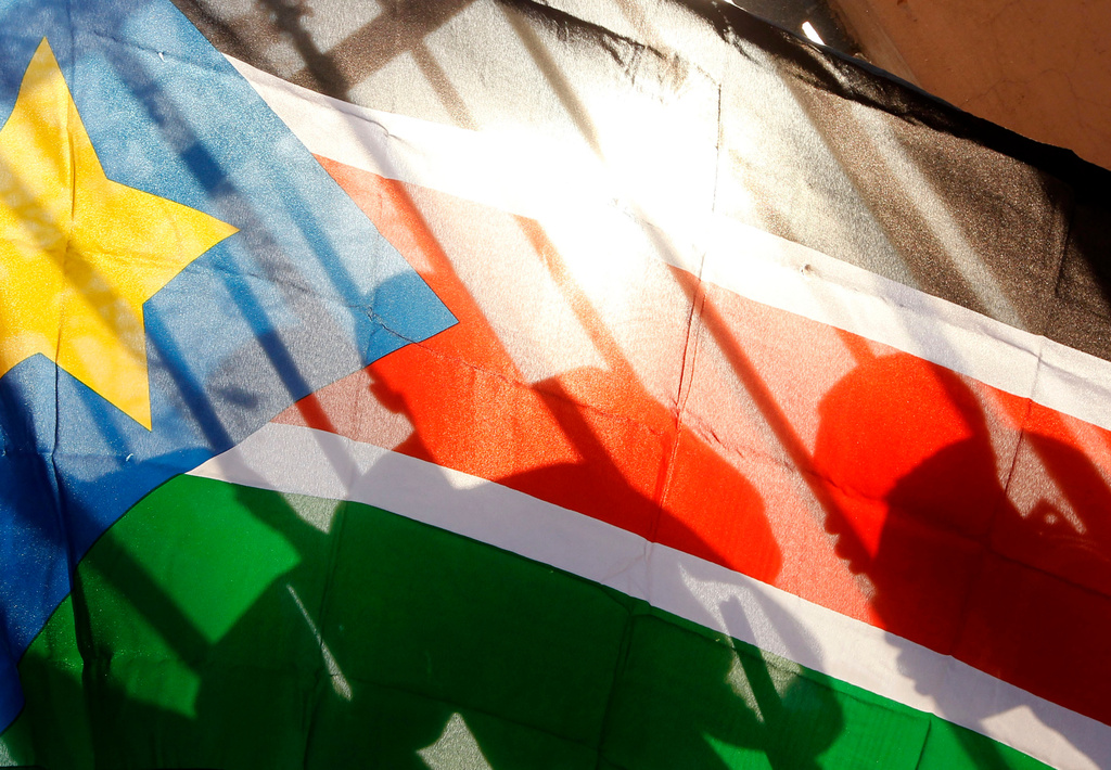 FILE - The silhouettes of South Sudanese people are seen through a South Sudanese flag as they line up to cast their votes in Juba, South Sudan, Jan. 9, 2011. (AP Photo/Jerome Delay, File)