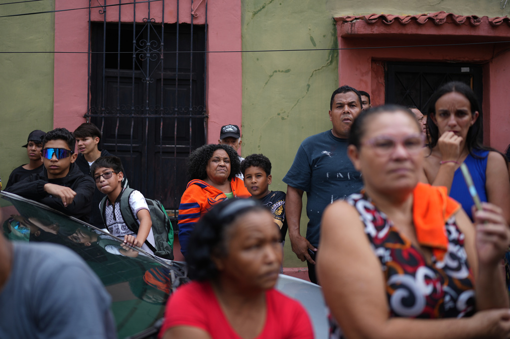 Neighbors stand outside the San Judas Tadeo school after part of the building collapsed in Caracas, Venezuela, Friday, July 3, 2026, days after it was damaged by the earthquakes. (AP Photo/Ariana Cubillos)
