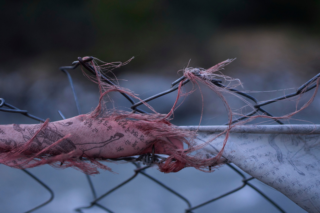 Torn Buddhist prayer flags are seen stuck on barbed wire that surrounds the Tibetan camp territory in Mustang, Nepal, April 19, 2025. (AP Photo/Niranjan Shrestha)