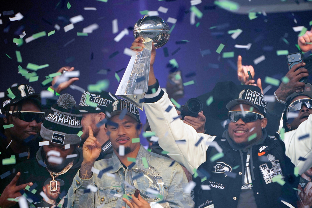 Seattle Seahawks wide receiver Jaxon Smith-Njigba, center left, stands with linebacker Uchenna Nwosu as he holds the Lombardi Trophy during the team's NFL football Super Bowl 60 celebration at Lumen Field, Wednesday, Feb. 11, 2026, in Seattle. (AP Photo/Stephen Brashear)