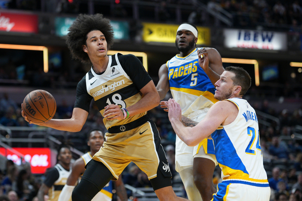 Washington Wizards forward Kyshawn George, left, passes around Indiana Pacers guard Garrison Mathews, right, during the first half of an NBA basketball game in Indianapolis, Sunday, Dec. 14, 2025. (AP Photo/AJ Mast)