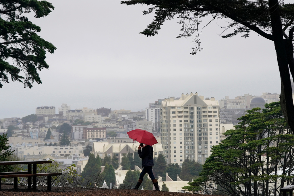 FILE - A woman carries an umbrella while walking at Alamo Square Park in San Francisco, Nov. 9, 2021. (AP Photo/Jeff Chiu, File)