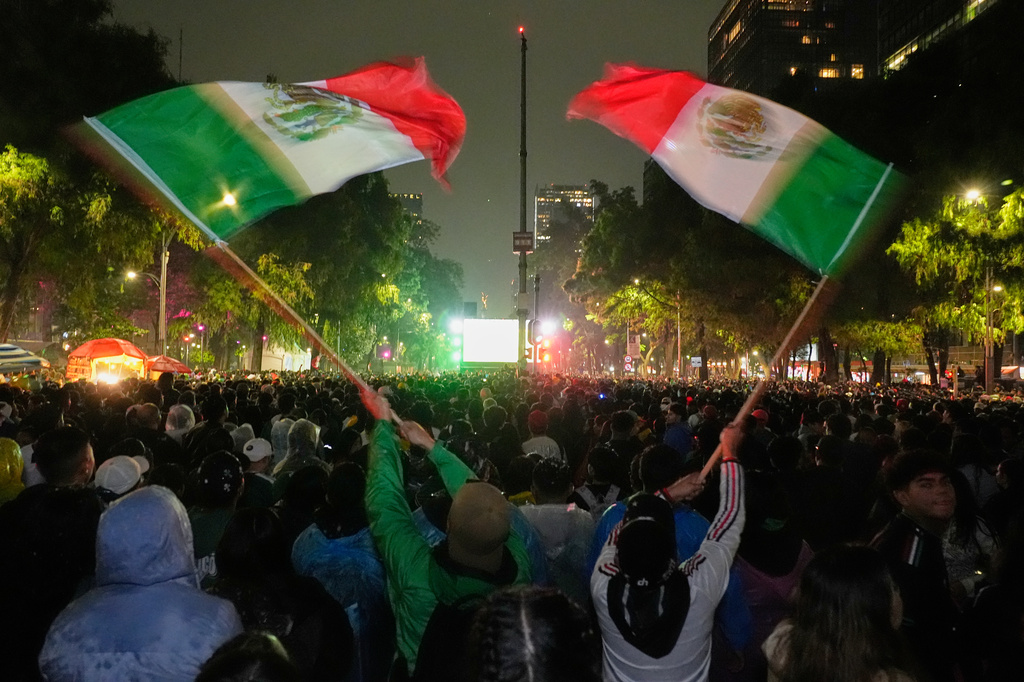Mexican fans wave flags as they watch the World Cup round of 32 soccer match between Mexico and Ecuador near the Angel of Independence monument in Mexico City, Tuesday, June 30, 2026. (AP Photo/Marco Ugarte)