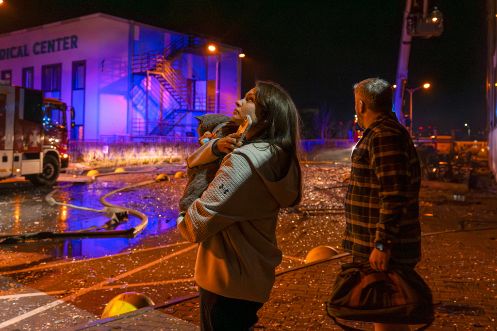 People watch as emergency services personnel work to extinguish a fire following a Russian attack in Kyiv, Ukraine, Tuesday, Nov. 25, 2025. (AP Photo/Dan Bashakov)