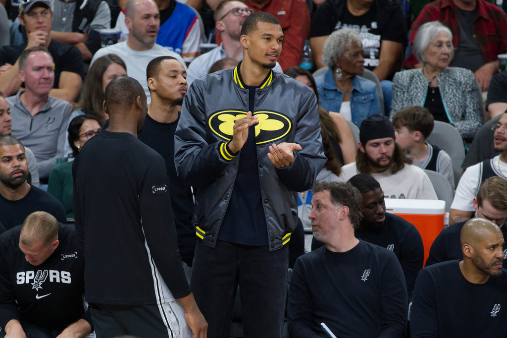 San Antonio Spurs center Victor Wembanyama watches play from the bench during the first half of an NBA basketball game against the Portland Trail Blazers, Wednesday, April 8, 2026, in San Antonio. (AP Photo/Darren Abate)