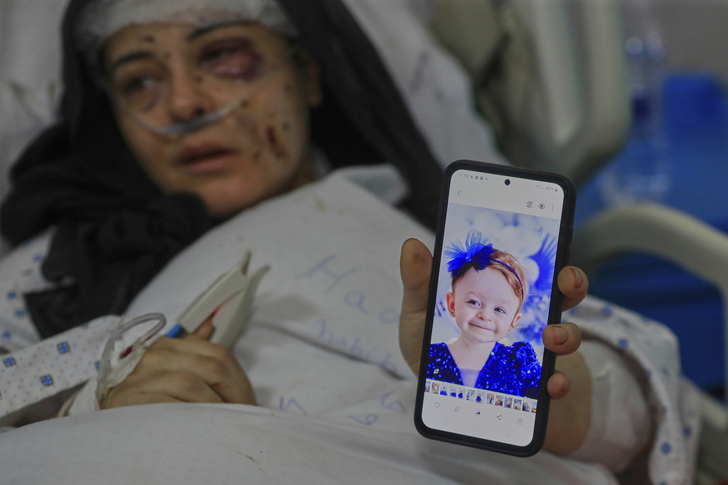 Amani Bazzi, who was injured Sunday in the town of Bint Jbeil, shows a portrait of one her three kids who were killed after an Israeli drone strike hit her family car, as she lies in Tibnin hospital, southern Lebanon, Monday, Sept. 22, 2025. (AP Photo/Mohammed Zaatari)