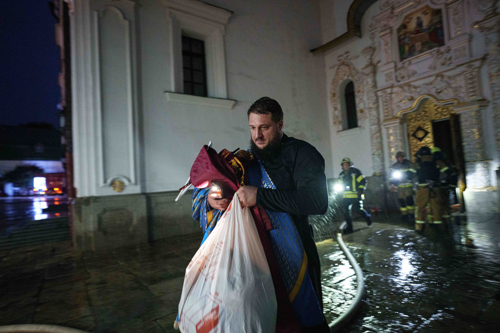 A priest carries church inventory out of the burning Dormition Cathedral of the Kyiv-Pechersk Lavra, also known as the Monastery of the Caves, during a Russian strike on Kyiv, Ukraine, on Monday, June 15, 2026. (AP Photo/Evgeniy Maloletka)