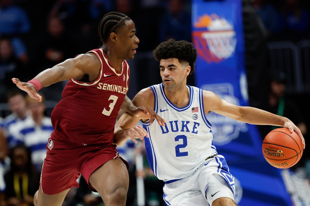 Duke guard Cayden Boozer (2) moves the ball against Florida State guard Thomas Bassong during the first half of an NCAA college basketball game in the quarterfinals of the Atlantic Coast Conference tournament in Charlotte, N.C., Thursday, March 12, 2026. (AP Photo/Nell Redmond)