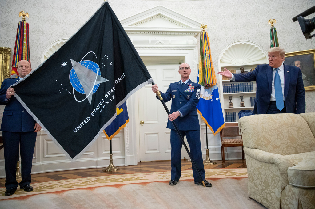 FILE - Gen. John "Jay" Raymond, Commander U.S. Space Command, left, and Chief Master Sgt. Roger Towberman, center, hold the Space Force Flag as President Donald Trump gestures to it during the presentation of the in the Oval Office of the White House in Washington on May 15, 2020. (AP Photo/Alex Brandon, File)