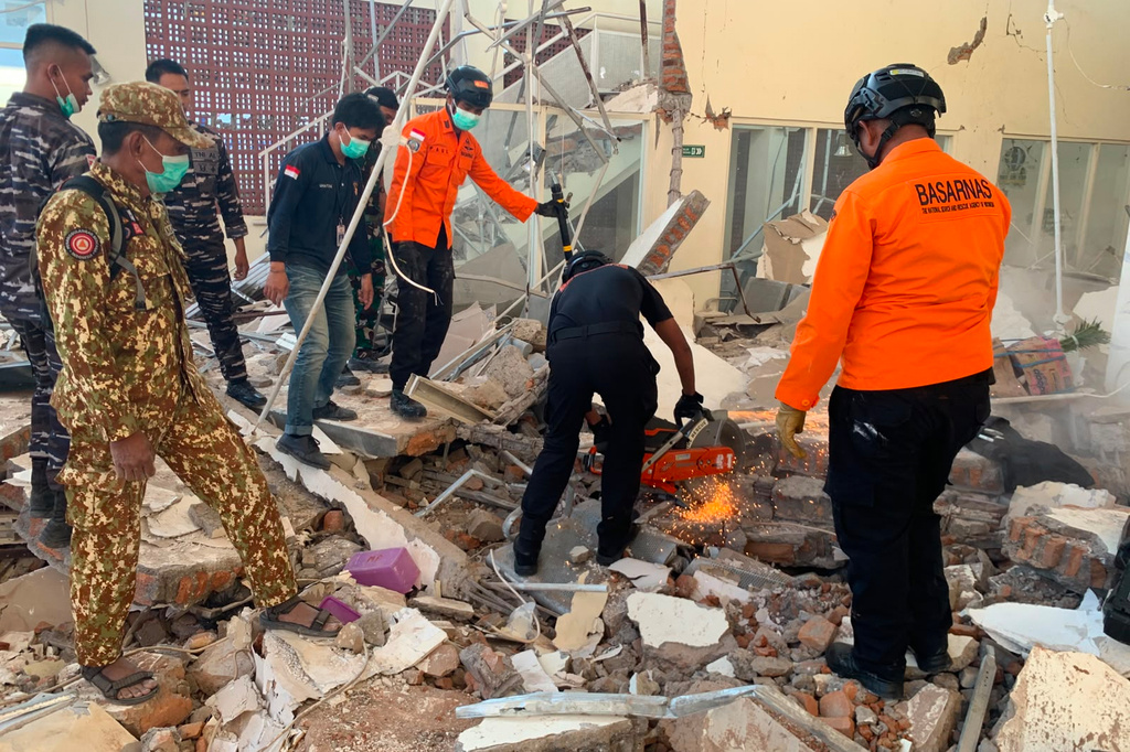 In this photo released by the Indonesian National Search and Rescue Agency (BASARNAS), rescuers attempt to clear debris at building damaged by an earthquake in Maumere, East Nusa Tenggara Province, Indonesia, Saturday, Aug. 15, 2026. (BASARNAS via AP)