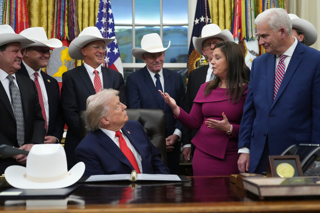 President Donald Trump talks to Rep. Elise Stefanik, R-N.Y., second from right, while Rep. Tom Emmer, R-Minn., far right, looks on during a bill signing ceremony with members of the 1980 U.S. Men's Olympic Hockey team Friday, Dec. 12, 2025, in the Oval Office of the White House, in Washington. (AP Photo/Jacquelyn Martin)
