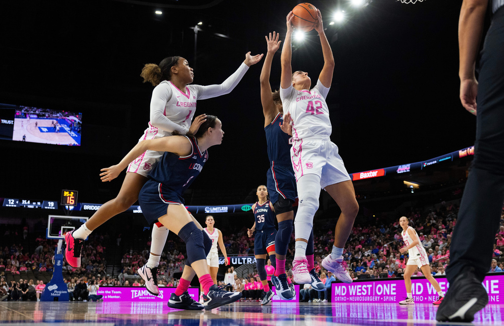 Creighton's Grace Boffeli (42)and Kendall McGee, top left, reach for a rebound against UConn's Kayleigh Heckel, bottom left, and KK Arnold, back right, during the first half of an NCAA college basketball game Sunday, Jan. 11, 2026, in Omaha, Neb. (AP Photo/Rebecca S. Gratz)