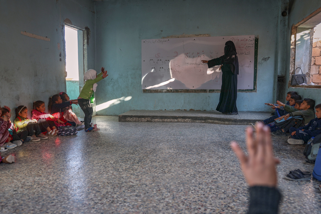 A teacher conducts a lesson with students inside a classroom of the Maar Shmarin Primary School in the village of Maar Shmarin, in the Idlib countryside, Syria, Sunday, Oct. 19, 2025. (AP Photo/Ghaith Alsayed)