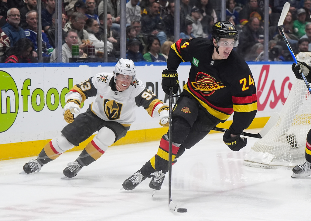 Vancouver Canucks' Zeev Buium (24) skates with the puck away from Vegas Golden Knights' Mitch Marner (93) during the second period of an NHL hockey game, in Vancouver, on Tuesday, April 7, 2026. (Darryl Dyck/The Canadian Press via AP)