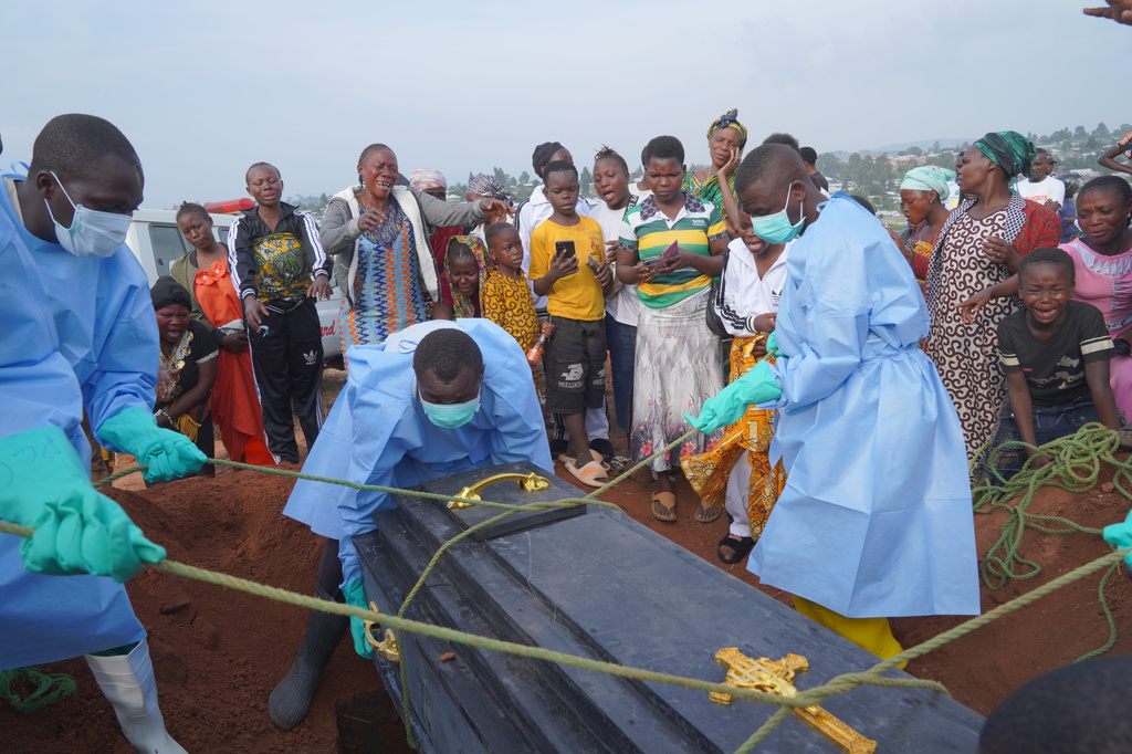 People dressed in protective gear lower into a grave the coffin containing the remains of Jeannine Katusabe, who died of Ebola, during a burial service in Bunia, Ituri province, eastern Congo, Tuesday, Aug. 11, 2026. (AP Photo/Dieudonne Dirole)