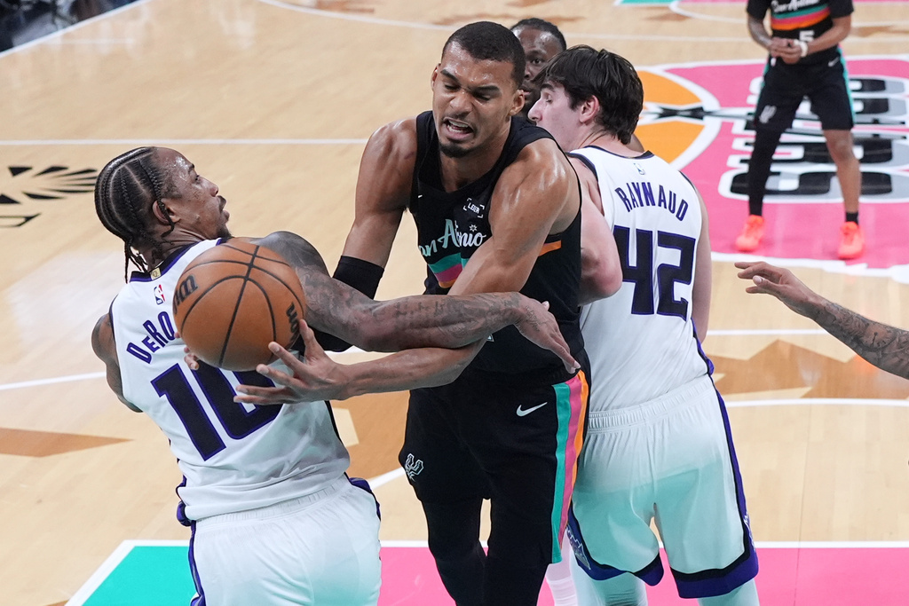 San Antonio Spurs forward Victor Wembanyama, center, is fouled by Sacramento Kings guard DeMar DeRozan (10) as he drives to the basket during the second half of an NBA basketball game in Austin, Texas, Saturday, Feb. 21, 2026. (AP Photo/Eric Gay)