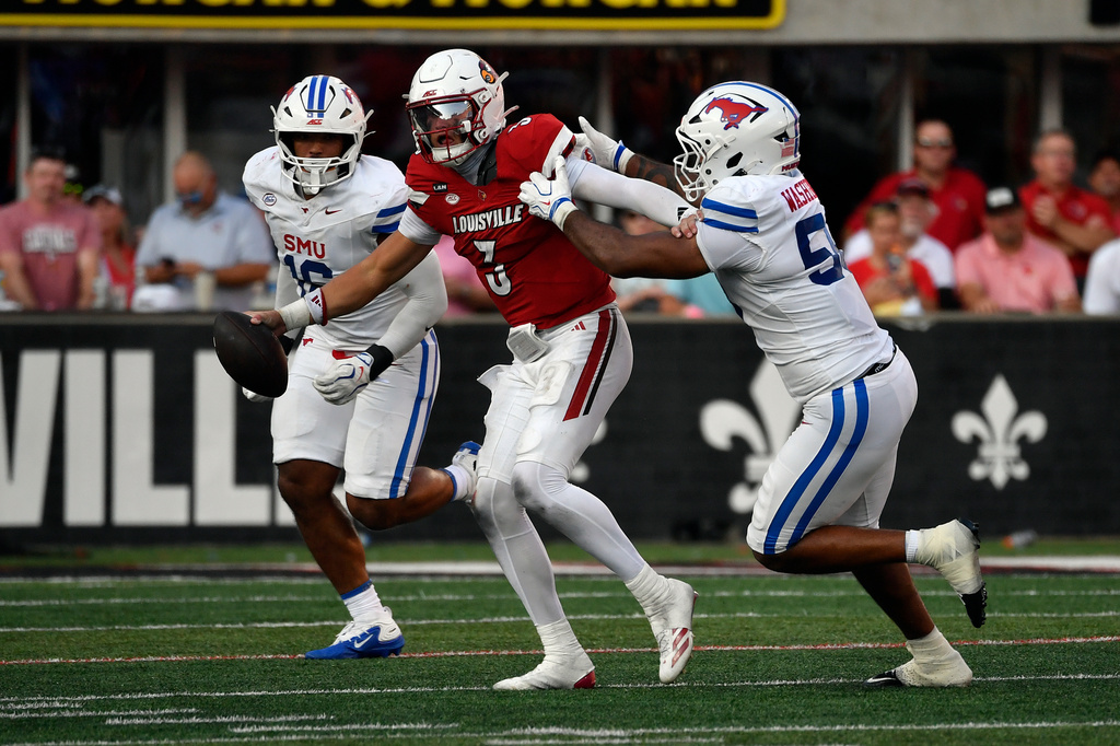 Louisville quarterback Lincoln Kienholz (3) attempts to avoid the tackle attempt by SMU defensive end Aakil Washington (58) during the second half of an NCAA college football game in Louisville, Ky., Saturday, Sept. 19, 2026. (AP Photo/Timothy D. Easley)