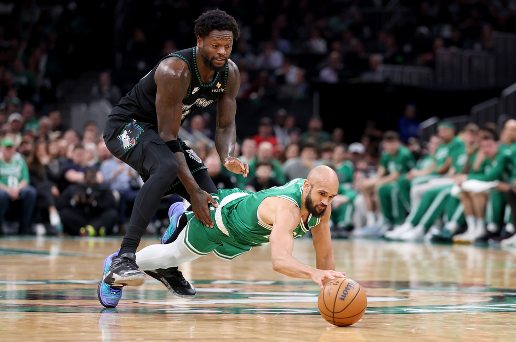 Boston Celtics guard Derrick White, right, dives for a loose ball in front of Minnesota Timberwolves forward Julius Randle, left, during the first half of an NBA basketball game, Sunday, March 22, 2026, in Boston. (AP Photo/Mark Stockwell)