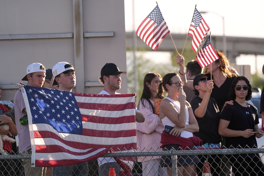People watch a hearse containing the body of Charlie Kirk, the CEO and co-founder of Turning Point USA, who was shot and killed on Wednesday leave after the body arrived aboard Air Force Two at Phoenix Sky Harbor International Airport, Thursday, Sept. 11, 2025, in Phoenix. (AP Photo/Ross D. Franklin)